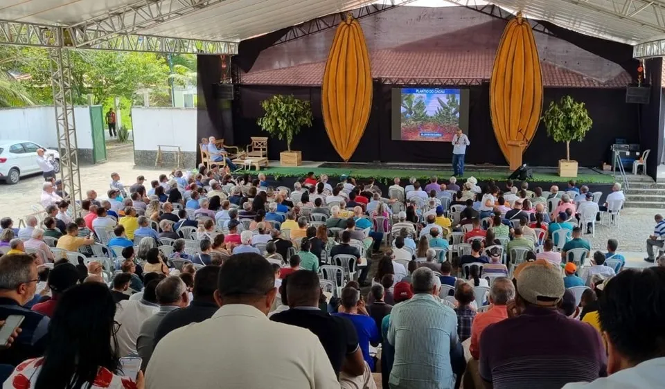 Pavilhão aberto da II edição em Itabuna, 2024, com plateia numerosa diante do palco decorado com painéis de cacau